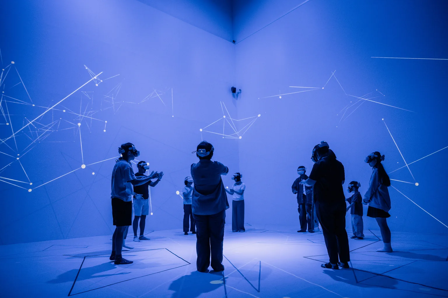 Participants in Shifting Connections wear headsets in a blue gallery surrounded by projected points and lines